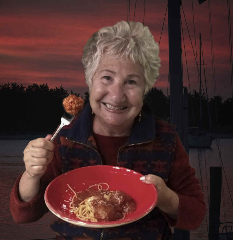 Patty, holding a plate of meatballs, in front of a red sunset.