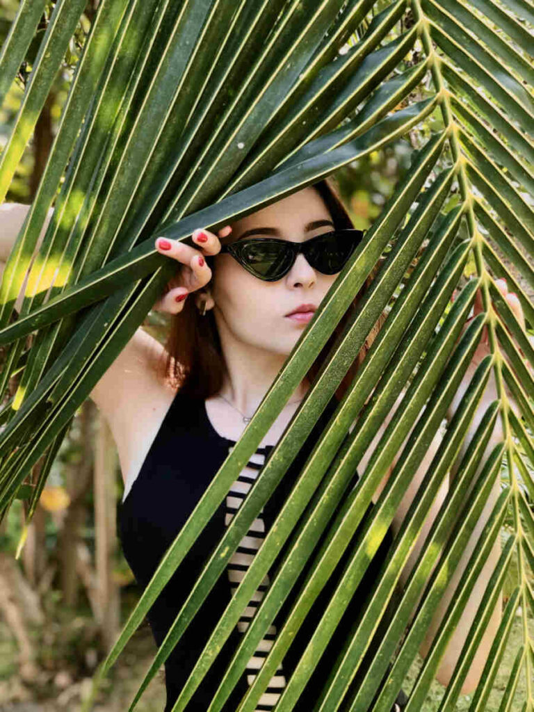 Woman peering through palm frond